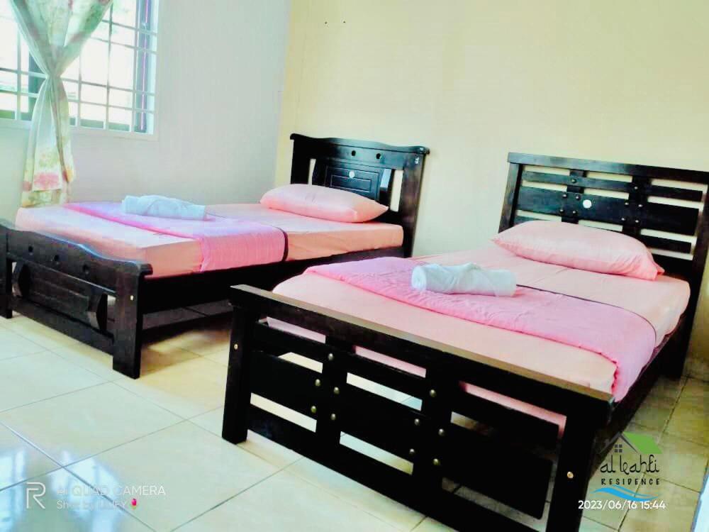 twee bedden in een kamer met roze lakens bij Qalya Homestay 1 @ Kota Bharu in Kota Bharu
