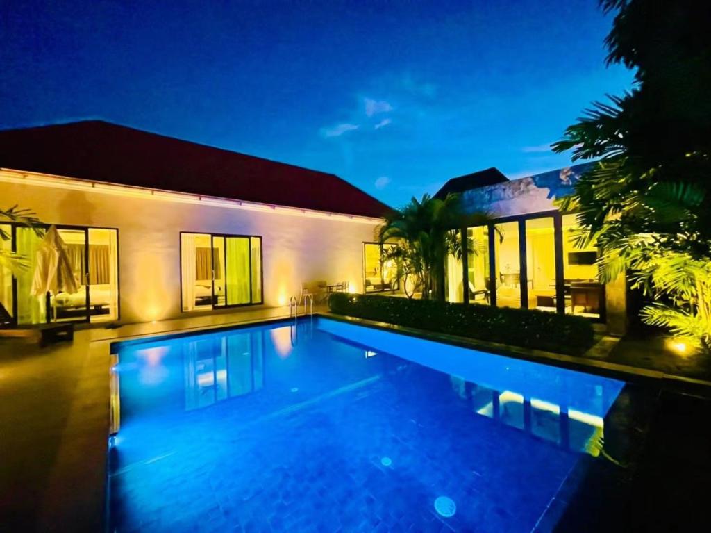 - une piscine en face d'une maison la nuit dans l'établissement E villa near bangtao beach ,普吉高端社区邦涛区度假村私人泳池别墅, à Bang Tao Beach