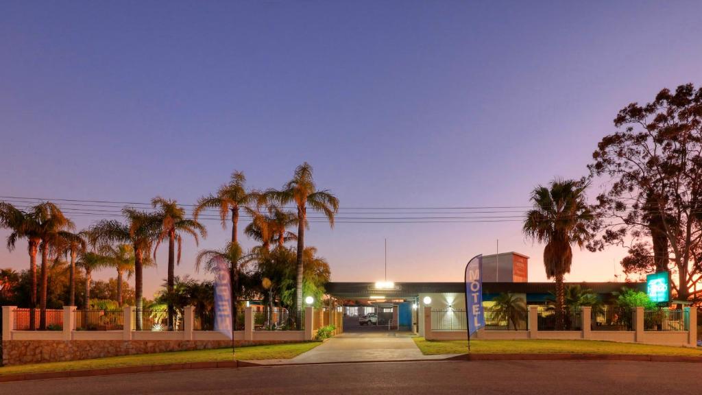 a gas station with palm trees in front of it at Hilltop Motel in Broken Hill