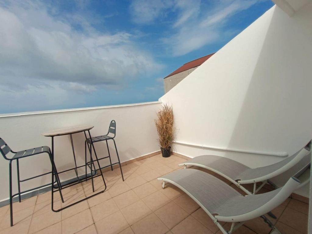 un balcón con sillas y una mesa en el techo en Cibuqueira numéro 8 , centre ville, vue sur mer, plage à pied en Le Moule