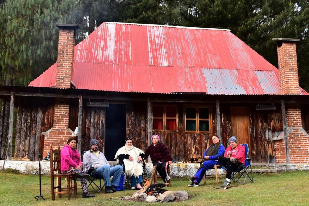 un groupe de personnes assises sur des chaises devant une maison dans l'établissement Rancho Ecológico El Mirador, à Acajete