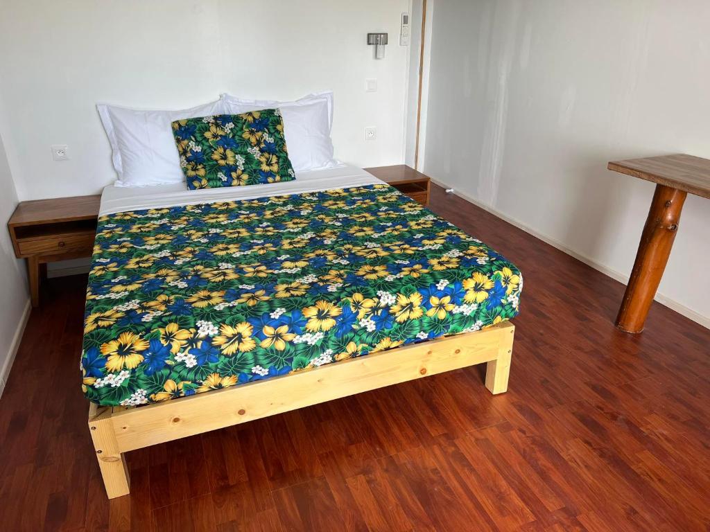 a bed with a floral comforter on it in a room at Te Mao in Avatoru
