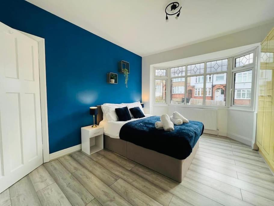 um quarto com uma parede azul e uma cama em Central Luton 4 Bedroom home✪parking✪By Hostaguest em Luton