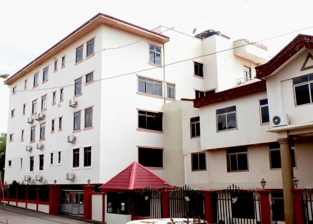 ein großes weißes Gebäude mit rotem Dach in der Unterkunft Mawuli Hotel in Obuassi
