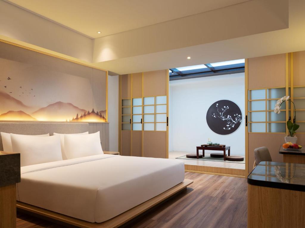 a bedroom with a large white bed and a window at Hotel Santika PasirKaliki in Bandung