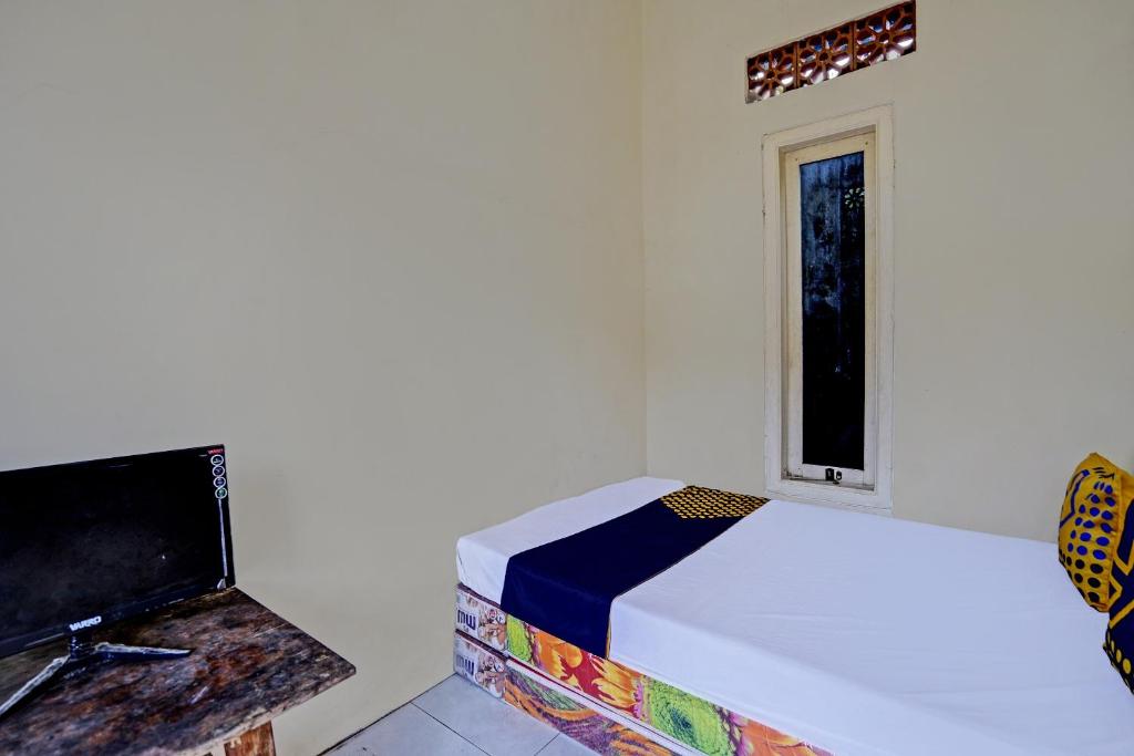 een kleine slaapkamer met een bed en een raam bij SPOT ON 92799 Tanjung Indah Homestay Syariah in Banyuwangi