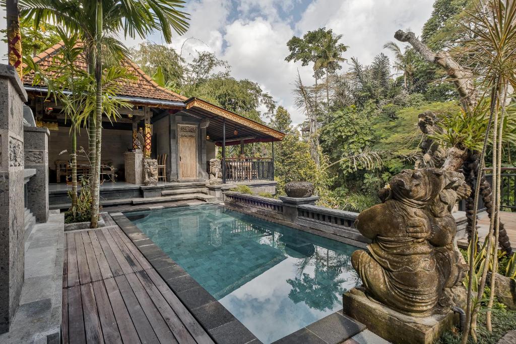 a pool in a villa with a statue in front of it at Tigata Ubud Cottage in Ubud