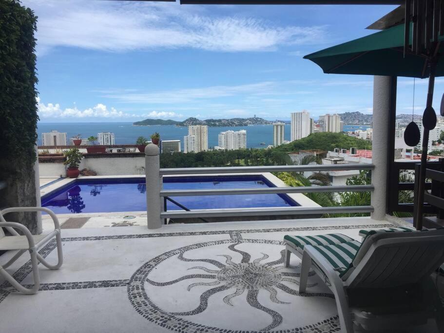 een patio met een tafel en stoelen en een zwembad bij Hermosa Villa Puesta al SOL in Acapulco