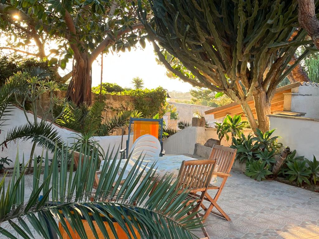 a patio with two chairs and a table and trees at Il GIARDINO della FALENA in Favignana