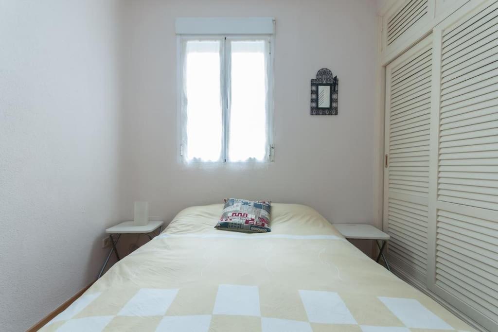 a white bedroom with a bed with a pillow on it at Precioso Apartamento in Madrid