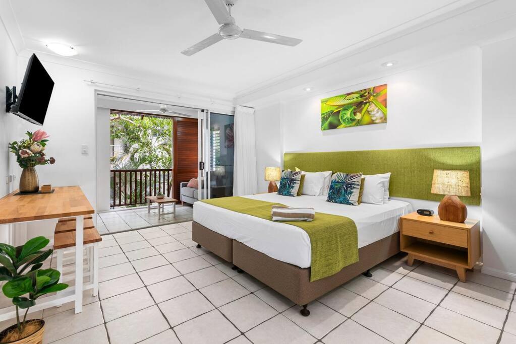 a bedroom with a large bed and a balcony at Palm Cove Treetop Spa Retreat in Palm Cove