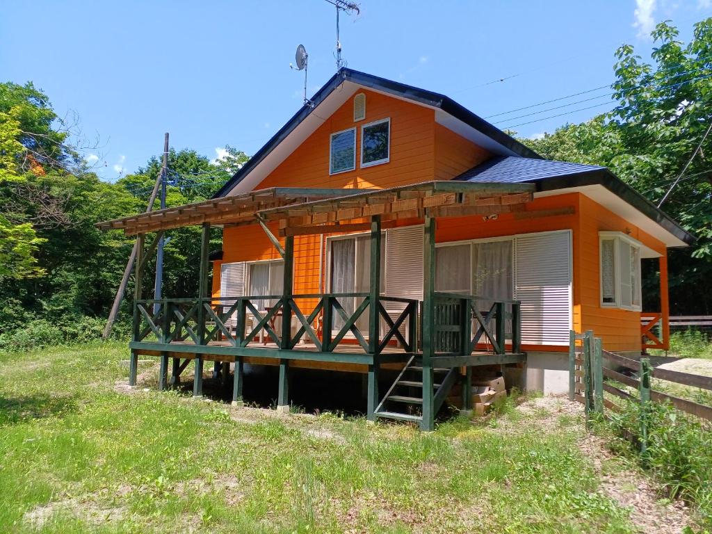 a small orange house with a porch and a balcony at コテージ　マリーゴールド in Nasu-yumoto