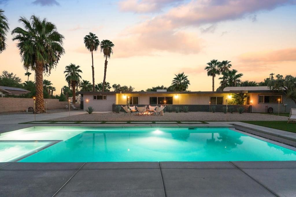 a swimming pool in front of a house with palm trees at Designer Hideaway in Borrego Springs