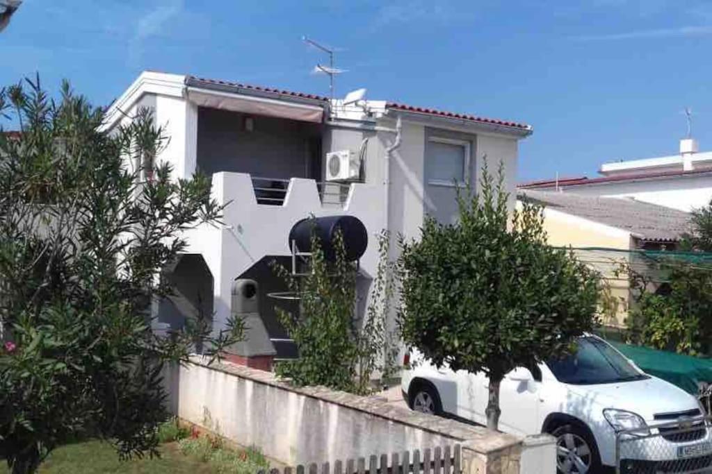 una casa bianca con un'auto parcheggiata davanti di Apartment Mona Vir a Vir (Puntadura)