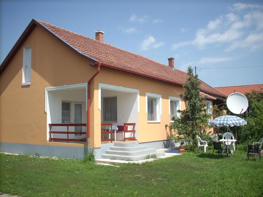 een klein geel huis met een trap en een tuin bij Abádi Karmazsin ház in Abádszalók