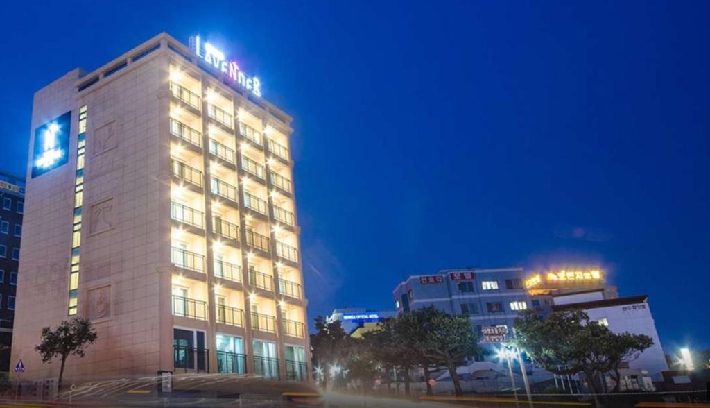 a building with a sign on top of it at night at Jeju Lavender Hotel in Seogwipo