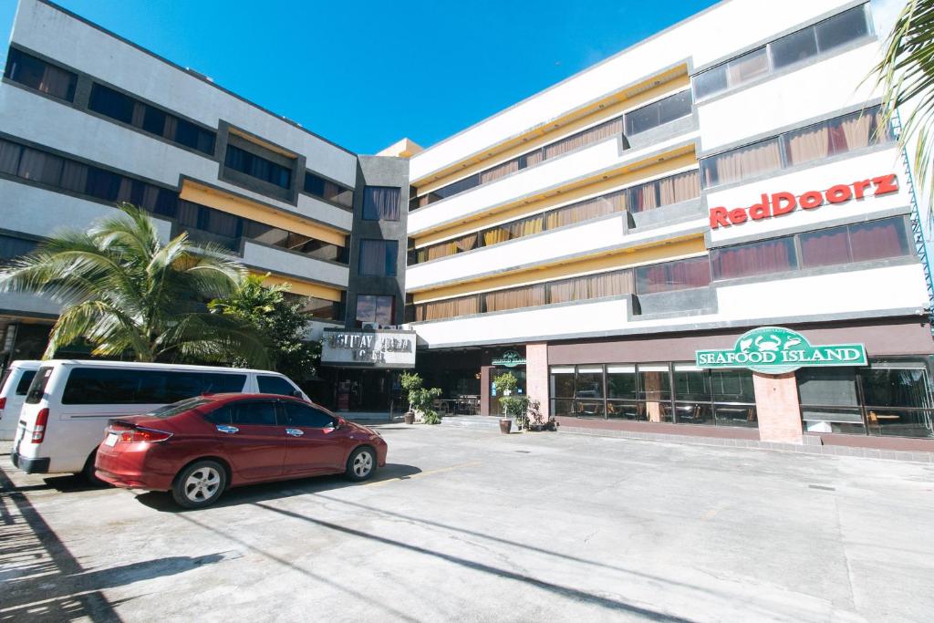 a red car parked in front of a building at RedDoorz Plus at Holiday Plaza Hotel Tuguegarao City in Tuguegarao City