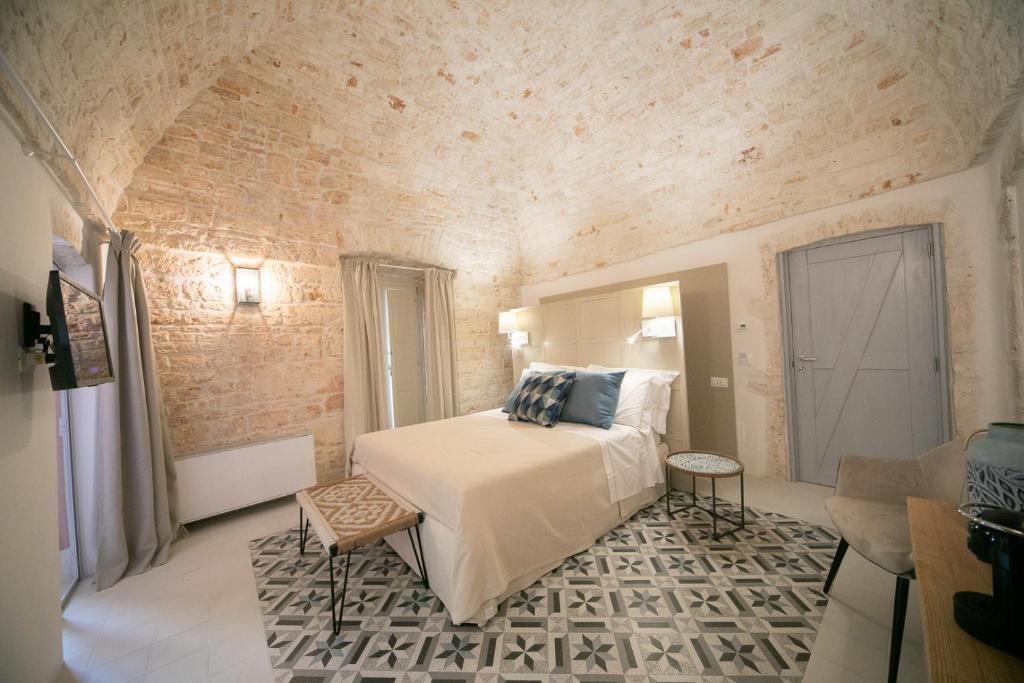 1 dormitorio con 1 cama en una habitación con una pared de ladrillo en San Marco Boutique Rooms, en Alberobello