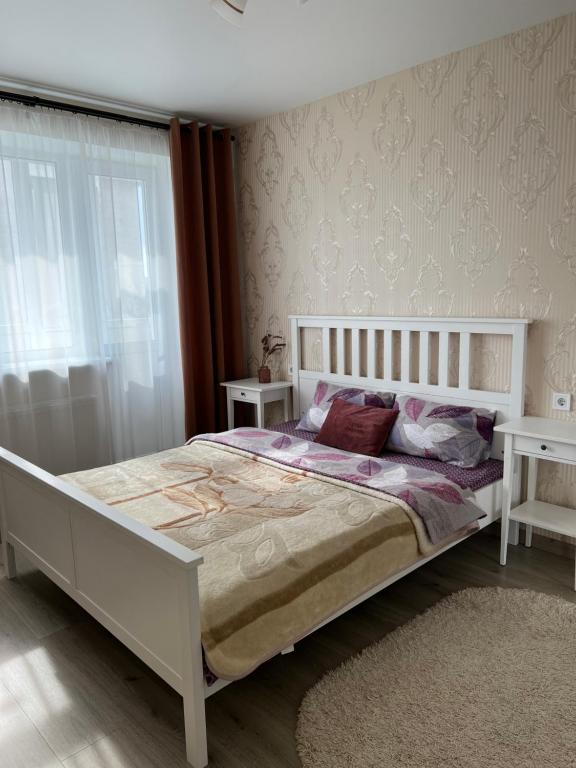 een slaapkamer met een groot wit bed en 2 tafels bij White Deluxe Apartments in Chernihiv