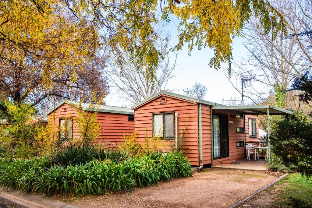 una pequeña casa de madera con porche en Mudgee Riverside Park, en Mudgee