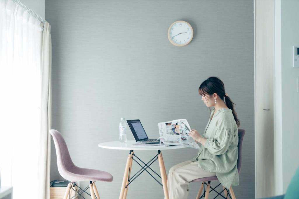 a woman sitting at a table with a laptop at YOUR ROOM Kumamoto Sta little 103 Vacation STAY 75704 in Kumamoto