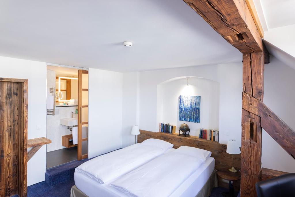 Schlafzimmer mit einem großen weißen Bett mit einem Kopfteil aus Holz in der Unterkunft Sorell Hotel Rüden in Schaffhausen