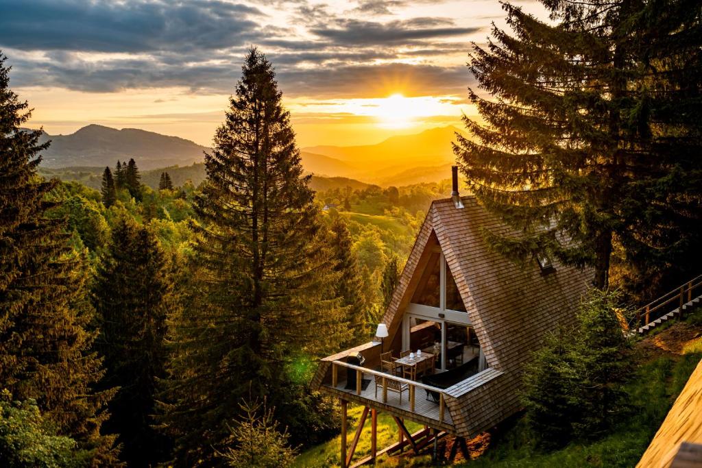 a house in the woods with the sunset in the background at Strajerii Verzi in Braşov