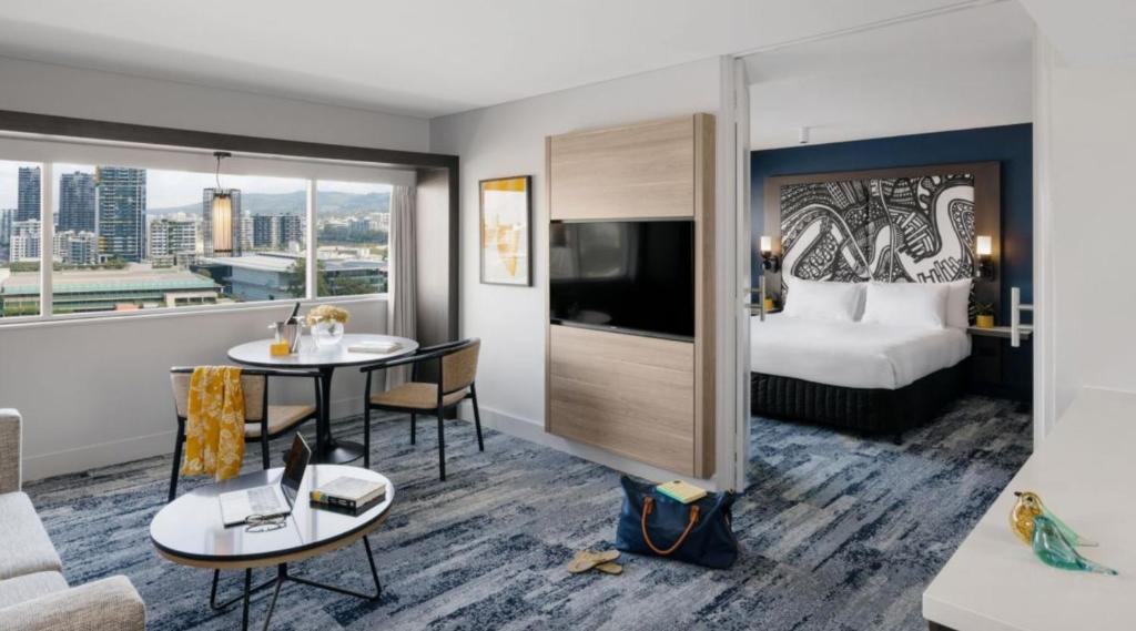 ブリスベンにあるvoco Brisbane City Centre, an IHG Hotelのベッド付きのホテルルームと景色を望む客室を提供しています。