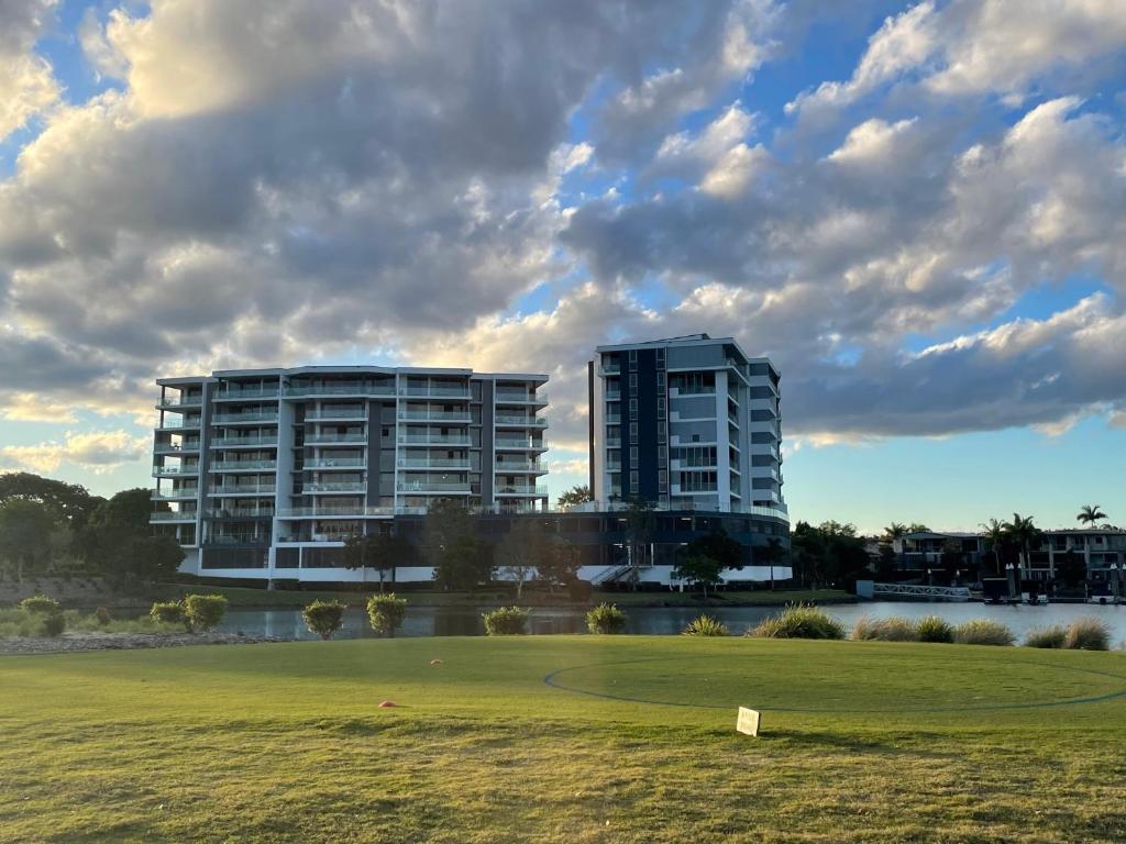 zwei hohe Gebäude vor einem grünen Feld in der Unterkunft Signature Waterfront Apartments in Gold Coast