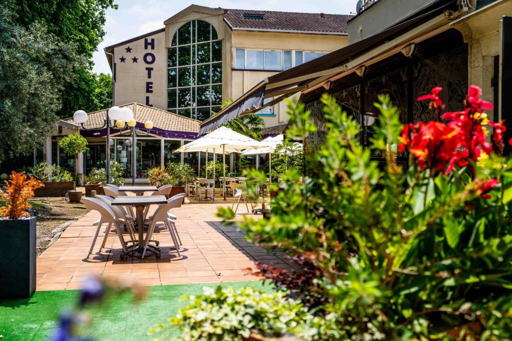 un patio avec des tables et des chaises en face d'un bâtiment dans l'établissement Logis Hôtel & Restaurant Ludik, à Bergerac