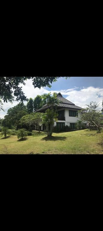 a large white house with trees in front of it at Pai Woodland Resort in Pai
