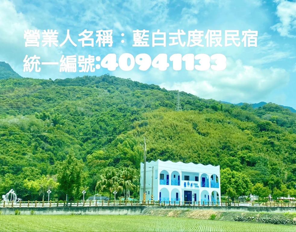 un panneau indiquant un bâtiment devant une montagne dans l'établissement Blue and White Style Holiday B&B, à Guanshan