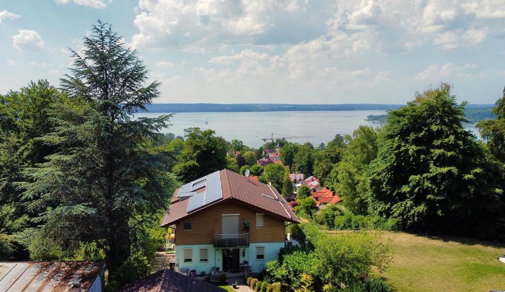 ein Haus auf einem Hügel mit Blick auf das Wasser in der Unterkunft Snug Stays - Traumhafter Seeblick, 2 Zi Apartment, Garten & Terrasse in Herrsching am Ammersee