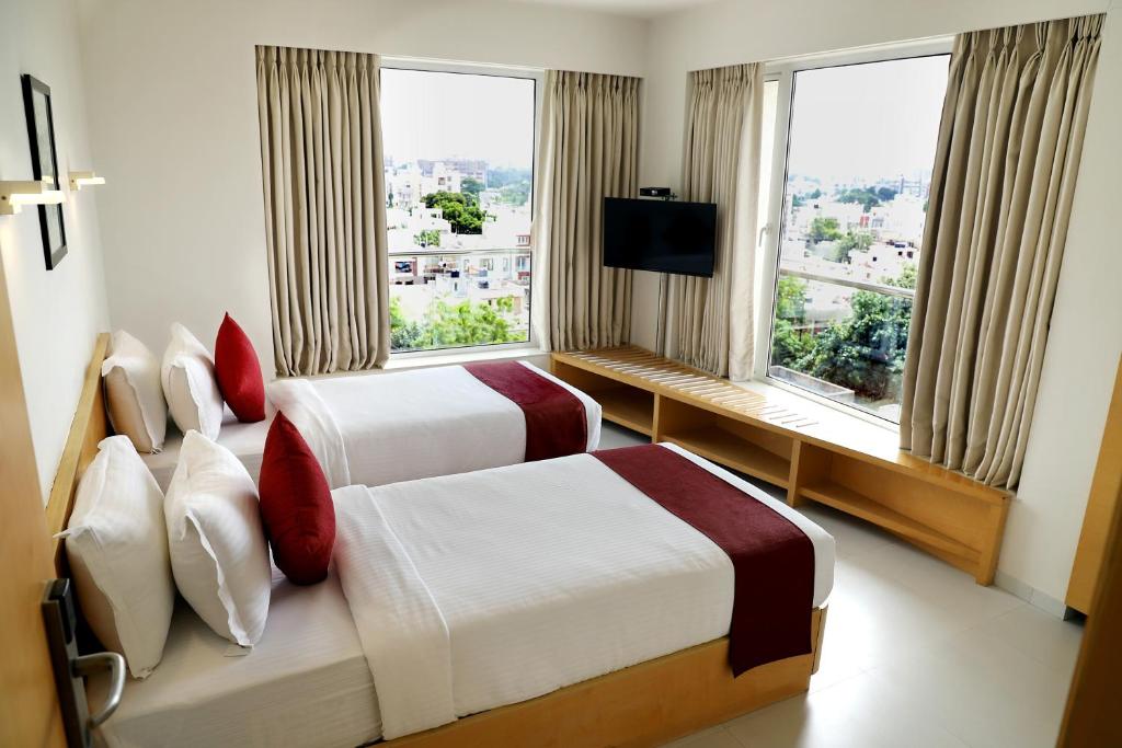 a hotel room with two beds and a window at Patria Suites in Rajkot