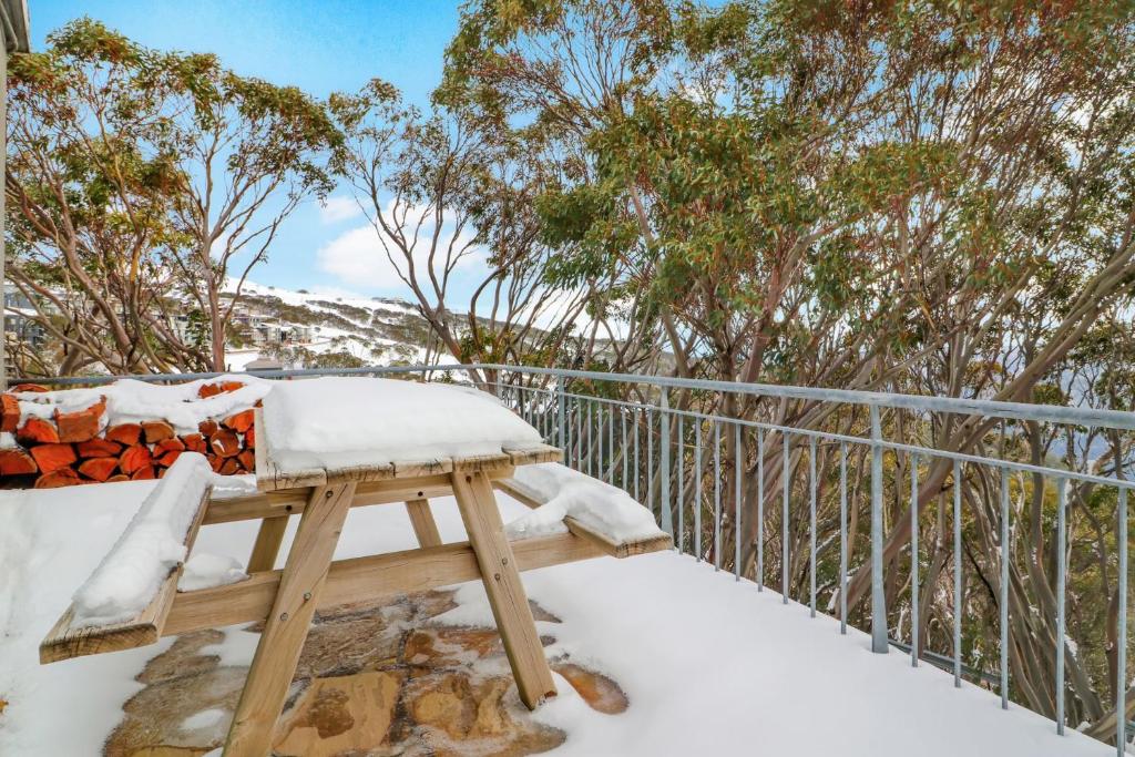 a snow covered bench on a balcony with trees at Mark II 2 West in Mount Buller