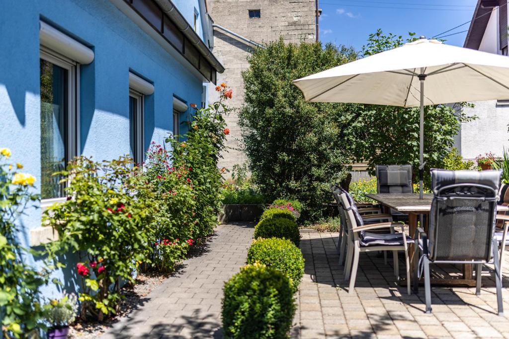 eine Terrasse mit einem Tisch, einem Sonnenschirm und Blumen in der Unterkunft Alb Rose Ferienwohnung in Sonnenbühl