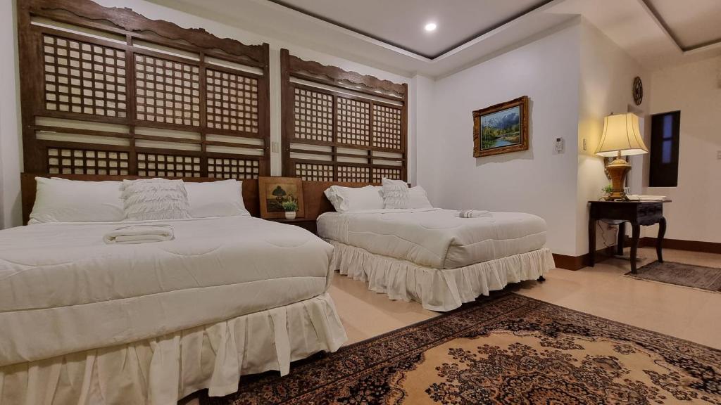 a bedroom with two beds and a table with a lamp at Residencia Orlina in Dumaguete