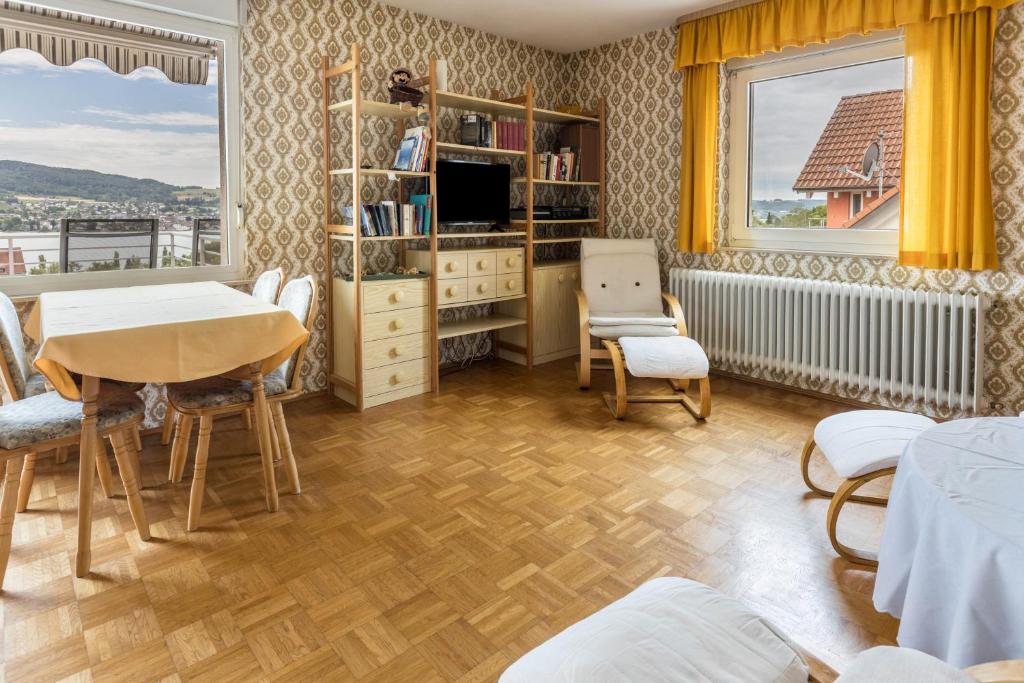 - un salon avec une table, des chaises et une télévision dans l'établissement See- Panorama, à Gaienhofen