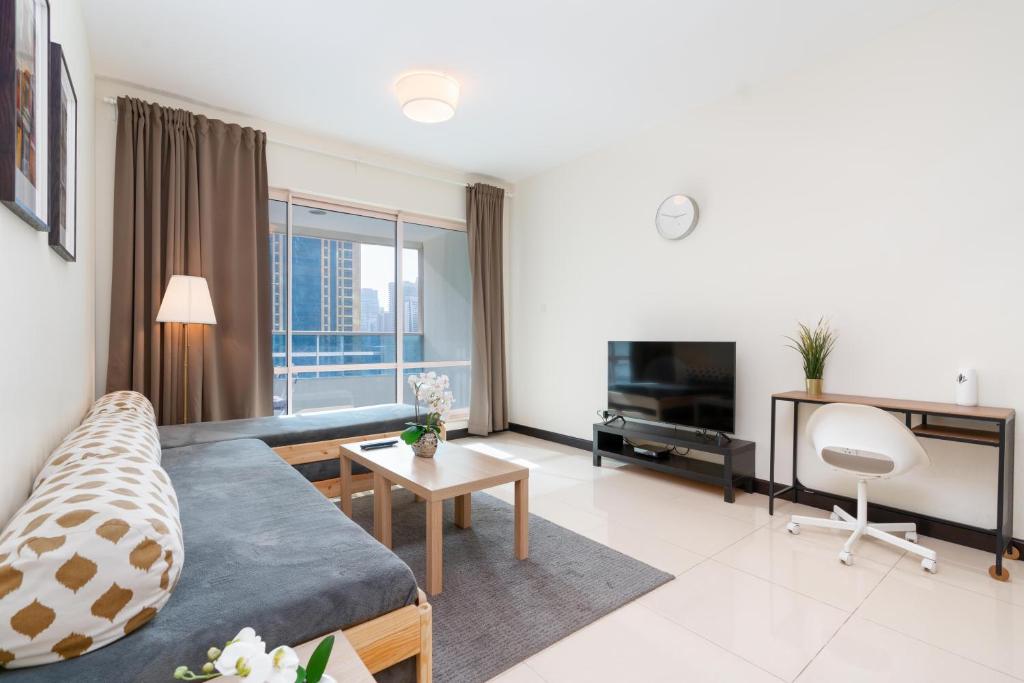 a large living room with a couch and a television at White Sage - Gorgeous Apartment in JLT Near the Metro Station in Dubai