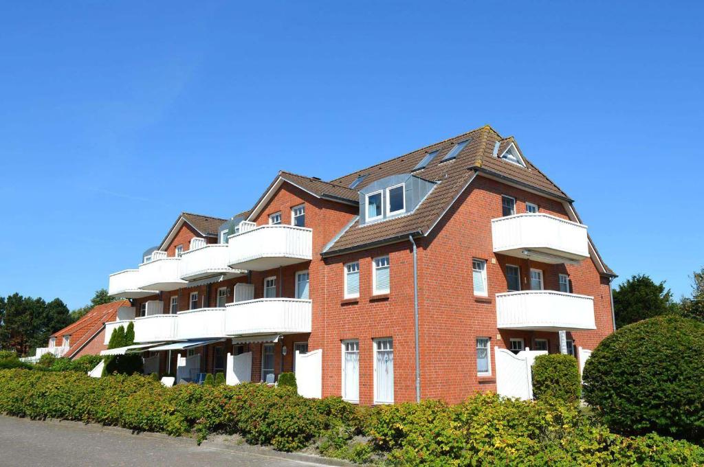 a large brick apartment building with white balconies at Zum Leuchtturm 10 Ferienwohnung Nr 05 in Westereck