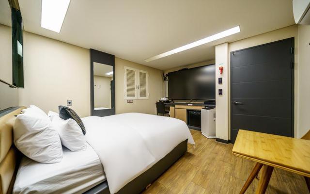 a bedroom with a large white bed and a kitchen at Bulgwang 3S Hotel in Seoul