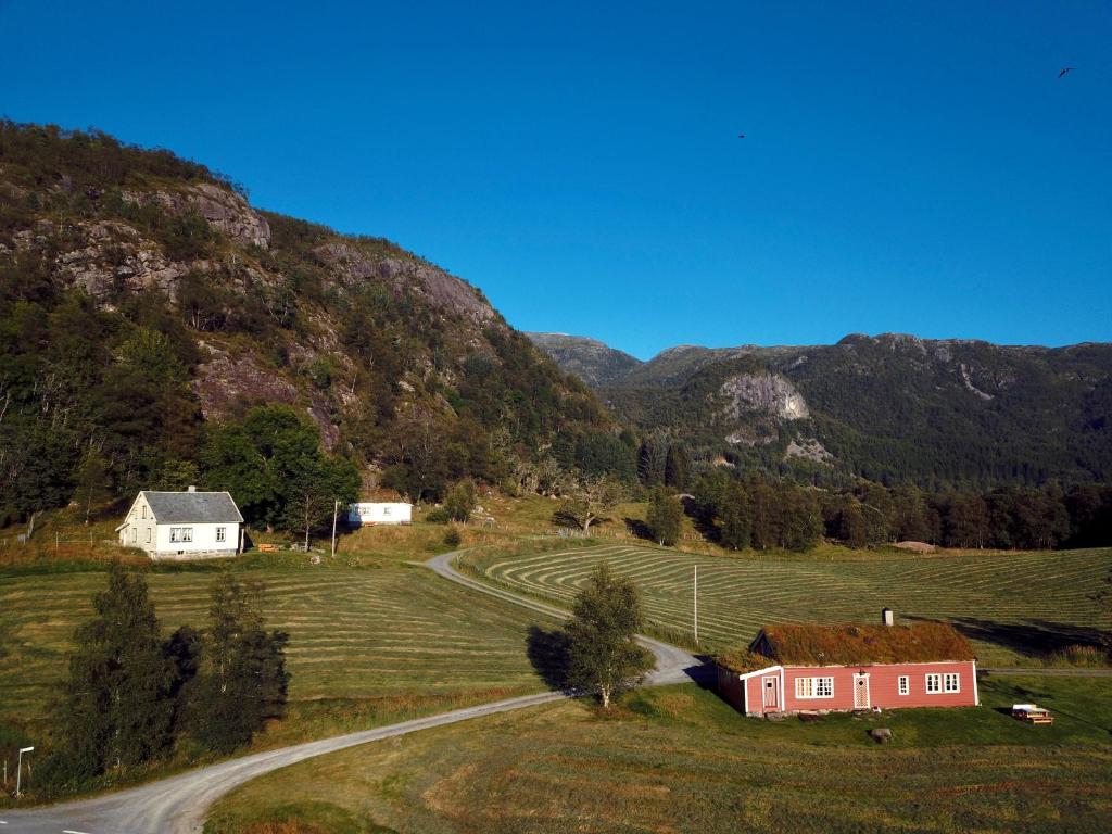 ein rotes Haus auf einem Feld mit Bergen im Hintergrund in der Unterkunft Fossane gard in Hjelmeland