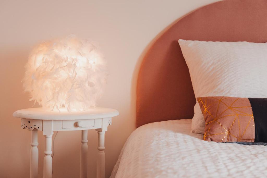 una lámpara blanca en una mesa junto a una cama en AU COIN DE PARADIS - Suite plume d'ange en Samer