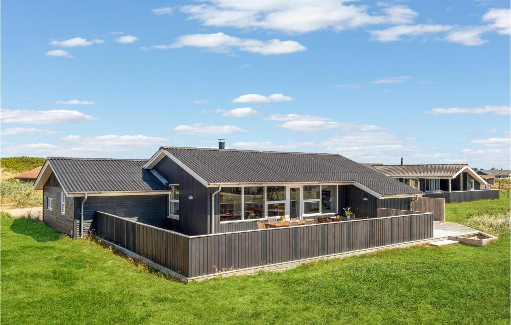 a house with a black roof on a green field at Beautiful Home In Hvide Sande With Wifi in Bjerregård