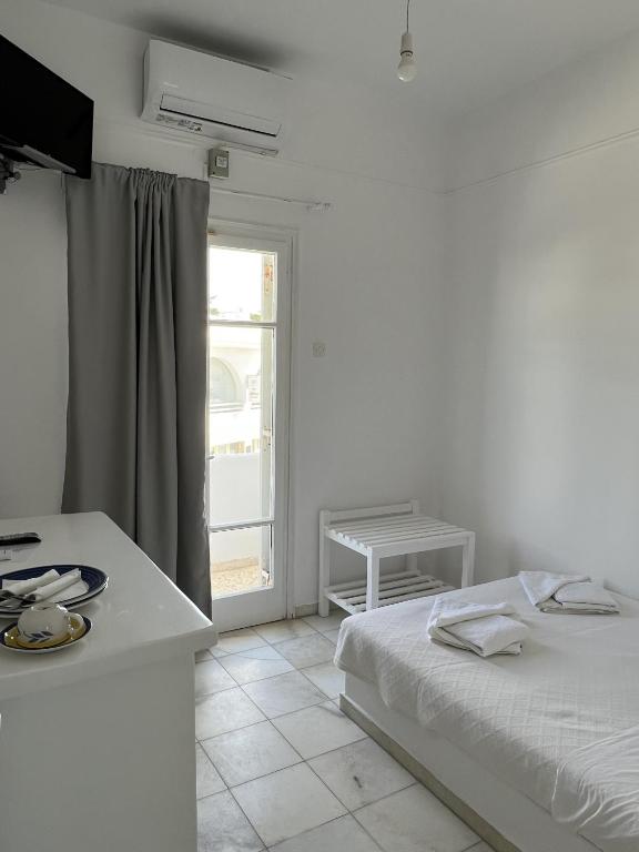 a white bedroom with a bed and a window at Hotel Anezina in Drios