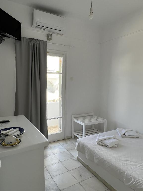 a white bedroom with a bed and a window at Hotel Anezina in Drios