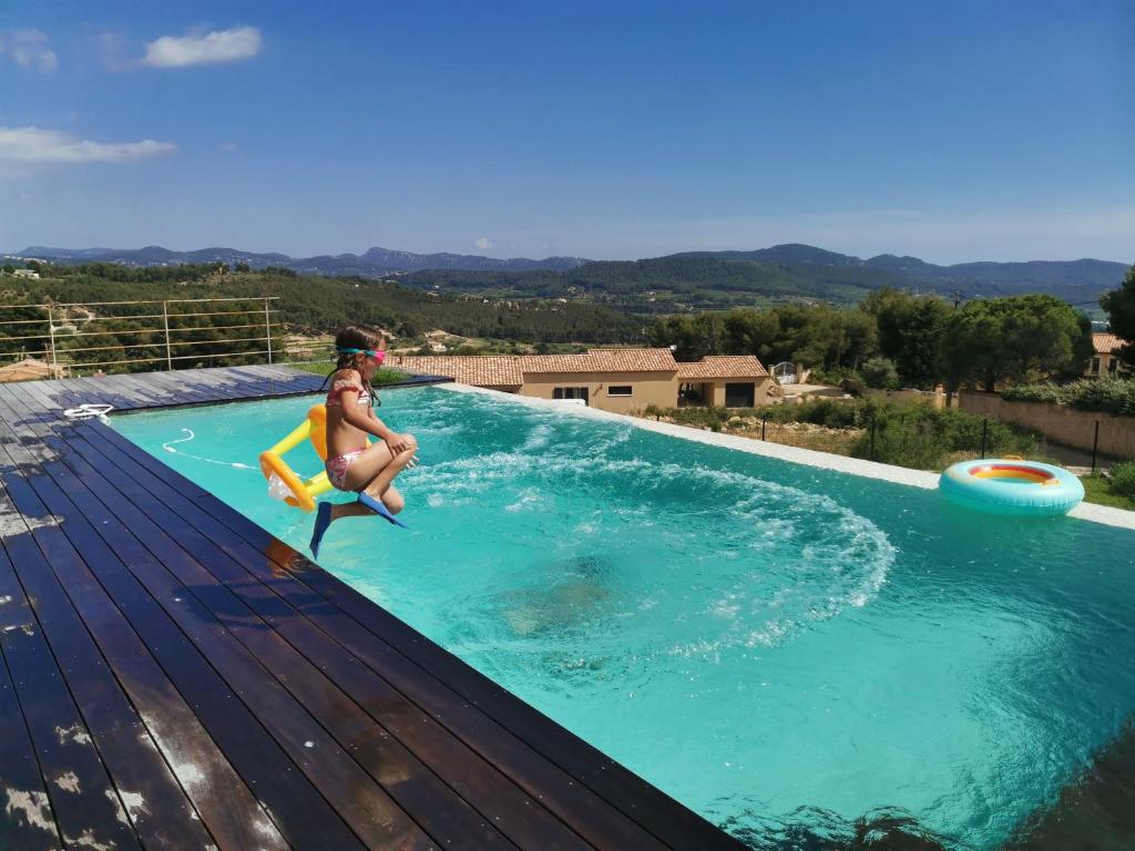 eine Frau springt in einen Swimmingpool in der Unterkunft Villa La Voile au Vent - Sur les collines de la Cadière d'Azur - Villa spacieuse, 4 chambres, climatisée avec piscine à débordement, Vue mer et collines in Laouque