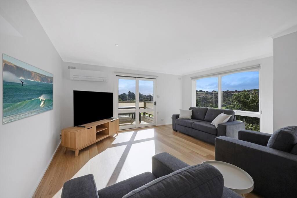 uma sala de estar com 2 sofás e uma televisão de ecrã plano em Logans Beach Apartments - Greenviews em Warrnambool