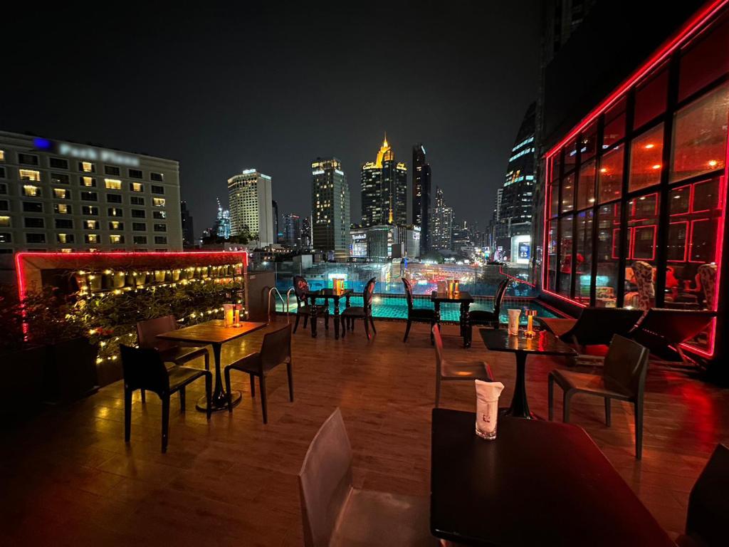 a rooftop bar with tables and chairs and a city skyline at Hotel Clover Asoke - SHA Extra Plus in Bangkok