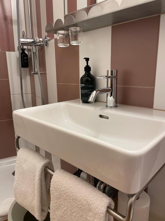 lavabo blanco en el baño con una botella de jabón en Hotel Adler Garni en Zernez